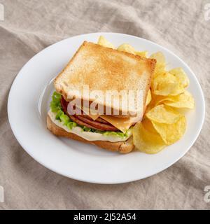 Hausgemachtes gebratene Bologna und Käse-Sandwich mit Chips auf einem Teller, Seitenansicht. Stockfoto