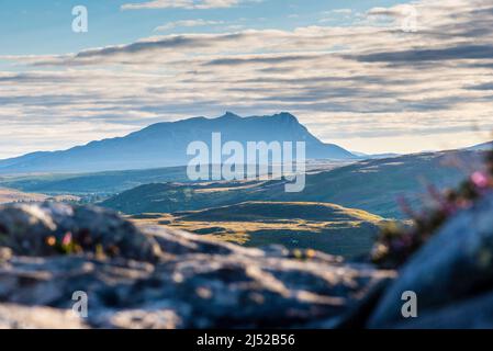 Die geringe Sonneneinstrahlung umrundt die Landschaft in einer Teleansicht südlich von einem Hügel an der Torrisdale Bay in Richtung der dunklen Silhouette von Ben Loyal am Horizont. Stockfoto