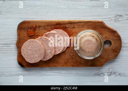 Hausgemachter Jagdwurst auf rustikalem Holzbrett auf weißem Holzhintergrund, Draufsicht. Flach liegend, über Kopf, von oben. Stockfoto