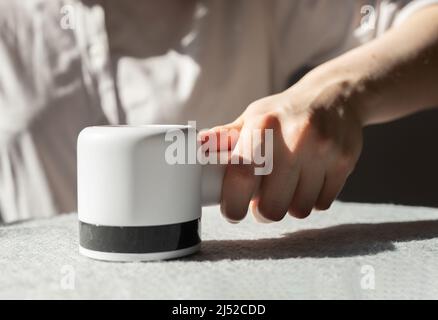 Weibliche Entfernung von Flusen aus Stoff mit dem Rasierer. Tragbarer Entfuszer. Elektronisches Gerät für Kleidung Pilling. Hochwertige Fotos Stockfoto