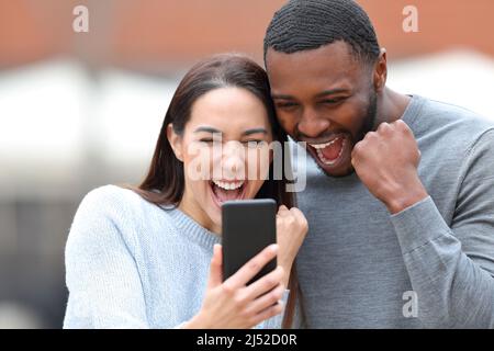 Aufgeregt interracial paar Überprüfung Smartphone auf der Straße Stockfoto