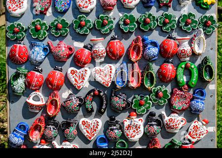 Eine Gruppe von bunten, handbemalten gemischten Magneten und Suvenirs, die auf einem traditionellen Wochenend-Markt in Bukarest, Rumänien, zum Verkauf angeboten werden Stockfoto