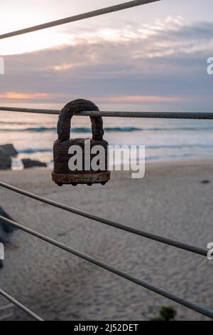 Das alte rostige masterlock hängt an einem Geländer auf der Treppe hinunter zum Garapatta State Beach Stockfoto