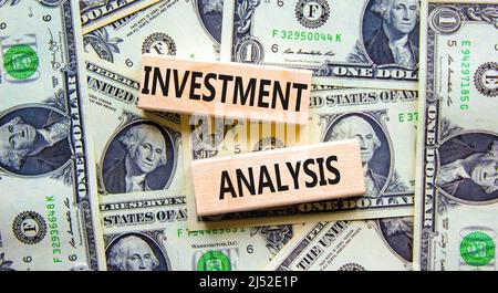 Symbol für die Investitionsanalyse. Holzblöcke mit Konzeptwörtern Investitionsanalyse auf schönem Hintergrund aus Dollarscheinen. Analyse der Unternehmensinvestitionen Stockfoto
