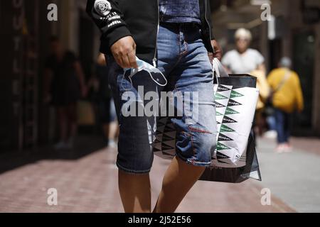 Palma, Spanien. 19. April 2022. Ein Mann trägt eine medizinische Maske in der Hand, während er durch die Innenstadt von Palma läuft. In Spanien ist es ab morgen, Mittwoch, dem 20. April, nicht mehr notwendig, fast überall eine Corona-Schutzmaske zu tragen. Auf Mallorca wird das Tragen einer Maske jedoch weiterhin in allen öffentlichen Verkehrsmitteln, Gesundheitseinrichtungen wie Gesundheitszentren, Krankenhäusern oder Apotheken obligatorisch sein. Quelle: Clara Margais/dpa/Alamy Live News Stockfoto