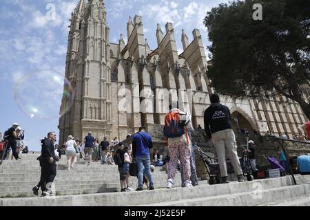 Palma, Spanien. 19. April 2022. Die Menschen gehen neben der Kathedrale von Palma de Mallorca. In Spanien wird ab morgen, Mittwoch, den 20. April, fast nirgendwo eine Corona-Schutzmaske getragen werden müssen. Auf Mallorca wird das Tragen einer Maske jedoch weiterhin in allen öffentlichen Verkehrsmitteln, Gesundheitseinrichtungen wie Gesundheitszentren, Krankenhäusern oder Apotheken obligatorisch sein. Quelle: Clara Margais/dpa/Alamy Live News Stockfoto