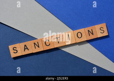 Sanktionen, Wort in Holzbuchstaben isoliert auf blauem und grauem Hintergrund Stockfoto