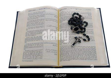 Katholischen Rosenkranz sitting on Top of eine offene Qu'ran. Stockfoto