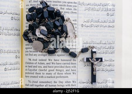 Katholischen Rosenkranz sitting on Top of eine offene Qu'ran. Stockfoto