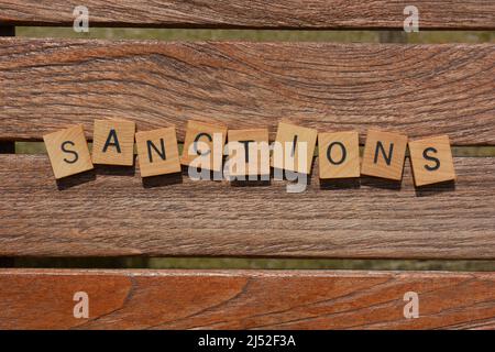 Sanktionen, Wort in Holzbuchstaben isoliert auf Holzlatten Hintergrund Stockfoto