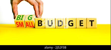 Großes oder kleines Budgetsymbol. Geschäftsmann dreht Holzwürfel und ändert Wörter kleines Budget zu großes Budget. Schöne gelbe Tabelle weißen Hintergrund, Kopie Stockfoto