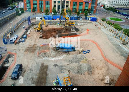 Baumaschinen einschließlich Bagger, Pfahlfahrer und Betonmischer auf einer Baustelle. Stockfoto