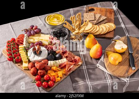 Die Aufspannung von Käse und Meze ist reich an verschiedenen Früchten, Käse, Fleisch und Crackern Stockfoto
