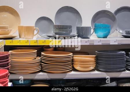 Reihen von verschiedenen grauen und beigen Tassen, Schüsseln und Tellern für zu Hause auf Regalen in einem Supermarkt. Gerichte werden im Laden verkauft. Stockfoto