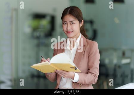Schöne asiatische Geschäftsfrau, die sich das pädagogische Webinar auf einem Laptop ansieht. Finanzierungskonzept. Stockfoto