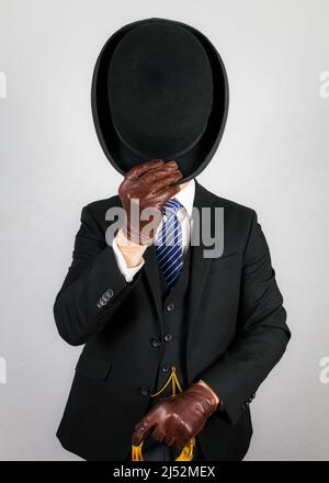 Porträt des britischen Butlers in dunklem Anzug elegant doffing Bowler Hut in höflicher Begrüßung. Vintage Style des englischen Gentleman. Stockfoto