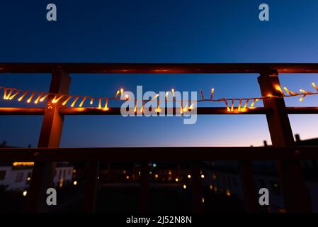 Weihnachtslichter am Geländer eines Balkons in der Nacht Stockfoto