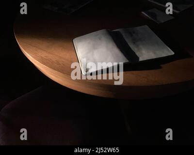 Wunderschönes, dramatisches Licht am frühen Morgen und ein leeres Tagebuch auf dem Tisch Stockfoto