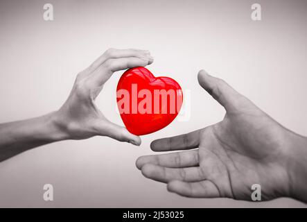 Hand, die einem anderen isoliert Herz gibt. Spendenkonzept Stockfoto