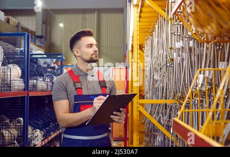 Mitarbeiter des Baustoffspeichers führt die Inventur von flexiblen Wasserschläuchen mit Metallauslauf durch. Stockfoto