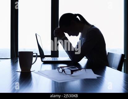 Müde und gestresste Geschäftsfrau an ihrem Schreibtisch. Druck bei der Arbeit, Gebetskonzept Stockfoto