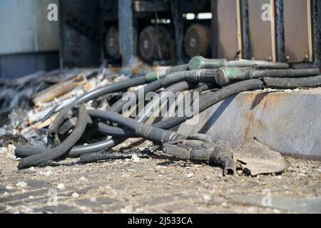 Verbrannte Füllschläuche und Pistolen liegen nach einem Brand in einer Tankstelle während des Krieges auf dem Boden. Stockfoto