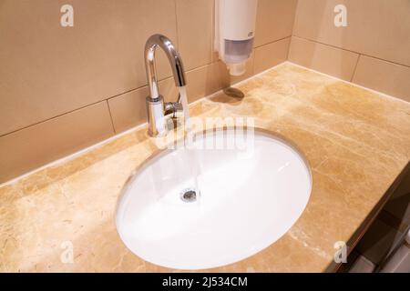 Fließendes Wasser aus dem Wasserhahn im Waschbecken in der Toilette Stockfoto