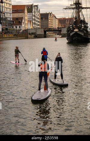 Danzig Polen März 2022 Gruppe von Sup-Surfern stehen auf Paddle-Board, Frauen stehen auf Paddeln zusammen in der Stadt Motlawa Fluss und Kanal in der Altstadt Danzig Polen. Tourismusattraktion Aktive Erholung im Freien Soziale Distanzierung Reiseziele Stockfoto