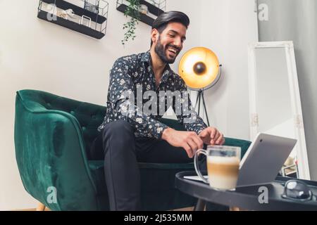 Junger männlicher Peson lächelt beim Surfen im Internet und sieht im Büro glücklich und aufgeregt aus. Hochwertige Fotos Stockfoto