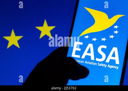 In dieser Abbildung ist das Logo der Europäischen Agentur für Flugsicherheit (EASA) auf einem Smartphone und im Hintergrund die Flagge der Europäischen Union (EU) zu sehen Stockfoto