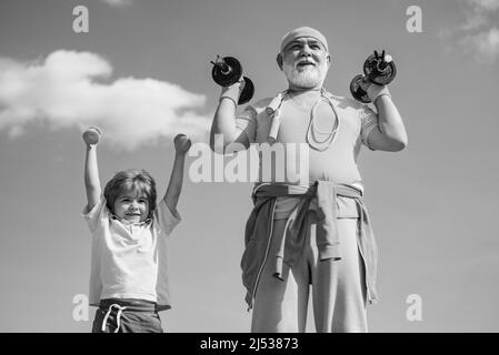 Sportübungen für Kinder. Hanteln anheben. Portrait von älteren Mann und niedlichen Kind Hanteln heben. Großvater und Sohn machen Übungen. Stockfoto