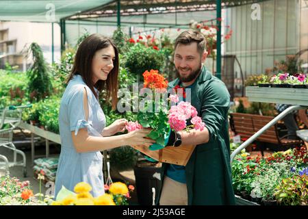 Mitarbeiter hilft weiblichen Kunden bei der Arbeit im Gartencenter Stockfoto