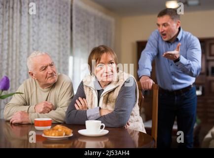 Mann schimpft seine älteren Eltern Stockfoto