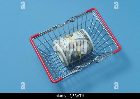 In einen Schlauch gerollte Dollars liegen in einem Einkaufskorb. Stockfoto