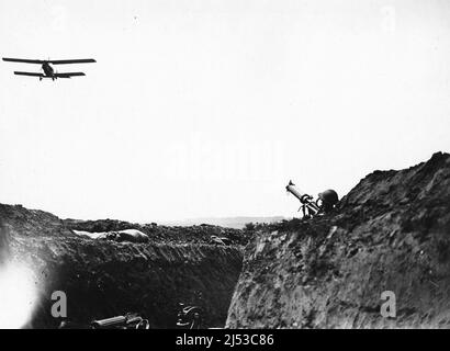 Ein Vickers-Maschinengewehr in den Schützengräben, das auf einen niedrig fliegenden Doppeldecker abzielt Stockfoto