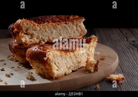 Hausgemachte Maiskuchen auf einem runden Holzbrettmit schwarzem Hintergrund und einer schwarzen Tasse Kaffee am Boden. Stockfoto