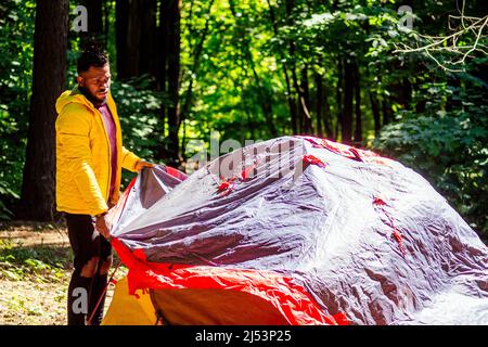 afroamerikanischer Mann in gelber Jacke mit Kapuze und Dreadlocks-Zöpfen. Stockfoto