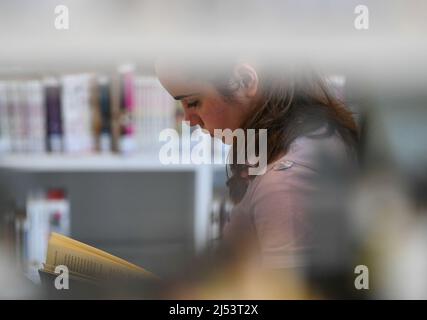 Stuttgart, Deutschland. 19. April 2022. Ein Mädchen liest am 19. April 2022 in der Stadtbibliothek Stuttgart ein Buch. Quelle: Lu Yang/Xinhua/Alamy Live News Stockfoto