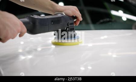 Polieren der Motorhaube. Auto Detaillierung und Polieren Konzept. Hände von professionellen Auto-Service männlichen Arbeiter, mit Orbitalpolierer, Polieren weißen Luxus Stockfoto