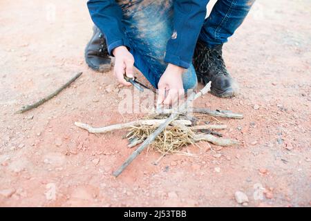 Ein Feuer mit einem Feuerstahl, Überlebens- und Abenteuerausrüstung, Outdoor-Fähigkeiten, Mann, der ein Lagerfeuer macht Stockfoto