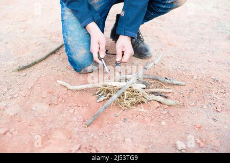 Ein Feuer mit einem Feuerstahl, Überlebens- und Abenteuerausrüstung, Outdoor-Fähigkeiten, Mann, der ein Lagerfeuer macht Stockfoto