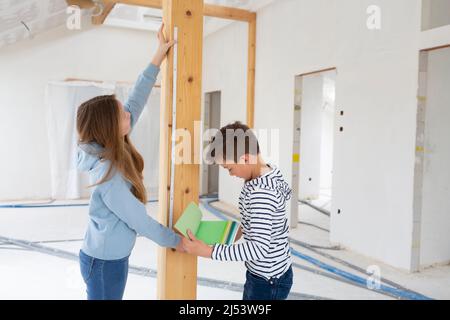Bruder und Schwester sind auf der Baustelle ihrer neuen Zimmer Loft-Wohnung mit Farbkarten und Klappregel und messen alles Stockfoto