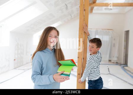 Bruder und Schwester sind auf der Baustelle ihrer neuen Zimmer Loft-Wohnung mit Farbkarten und Klappregel und messen alles Stockfoto