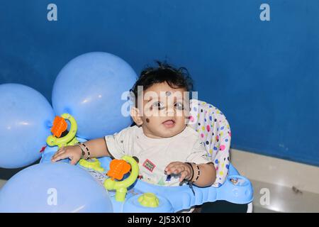 Chennai Tamilnadu, Indien . 02. Januar 2022.Nahaufnahme eines kleinen indischen Neugeborenen, der in einem mit einer blauen Kugel geschmückten Spaziergänger sitzt Stockfoto