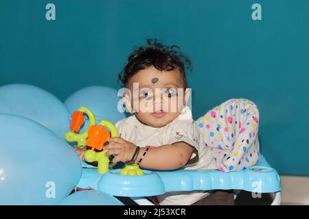Chennai Tamilnadu, Indien . 02. Januar 2022.Nahaufnahme eines neugeborenen indischen Jungen, der in einem mit blauen Luftballons geschmückten Spaziergänger sitzt Stockfoto