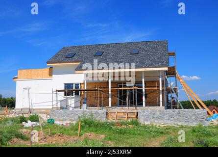 Renovieren und reparieren Wohnhausfassade Wand mit Mineralwolle Isolierung, Verputzen, Malerei Wand. Hausbau mit Asphaltschindeln ro Stockfoto