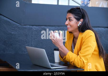 Junge lateinamerikanische Geschäftsfrau, die Musik hört, während sie in einem Café arbeitet. Stockfoto
