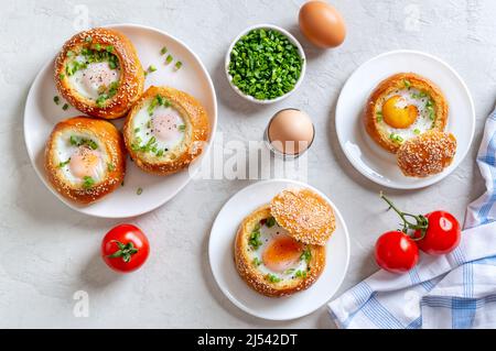 Gebackene Brötchen gefüllt mit Eiern und Speck auf Tellern auf hellem Hintergrund. Frühstück a la Carte. Draufsicht. Stockfoto