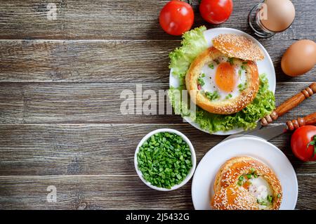 Gebackene Brötchen gefüllt mit Eiern und Speck auf Tellern auf Holzboden. Leckeres und schnelles Frühstück. Gesunde Ernährung Konzept. Food Hintergrund mit c Stockfoto