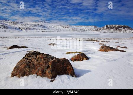 Verschneite Winterszene aus Island. Weiße Landschaft mit dunklem Stein und Blau mit weißen Wolken. Klarer Tag mit Schnee-Eis-See. Schneebedeckter Berg in der Isländer Stockfoto